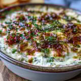 Warm Smoked Gouda & Onion Dip features a golden-brown crust and chopped chives, perfect for a cozy party appetizer spread.