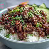 Spicy Korean Ground Beef Bowl with sizzling gochujang beef, colorful veggies, and toasted sesame seeds on a dark plate.