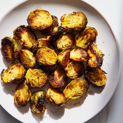 Roasted Brussels Sprouts served warm in a rustic bowl, garnished with optional Parmesan and lemon zest. 