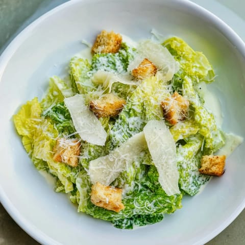 Close-up of a classic Caesar Salad topped with golden croutons and freshly grated Parmesan cheese served in a bowl.