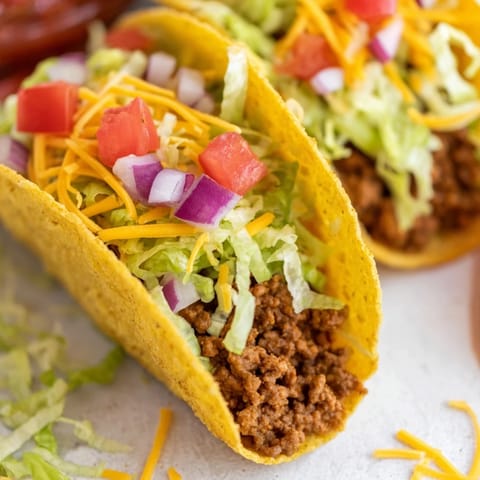 A plate of American-Style Tacos ready for a family dinner, topped with fresh tomato and zesty salsa.