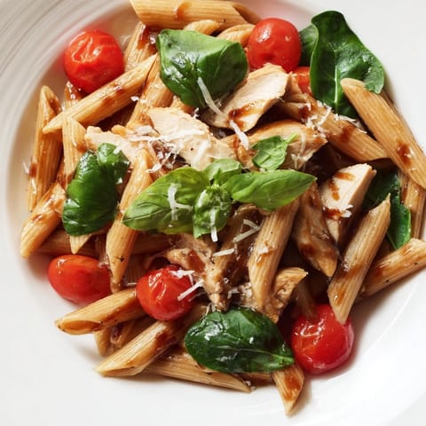 Steaming bowl of Balsamic Glazed Chicken Pasta featuring juicy glazed chicken strips, penne tossed in a tangy balsamic reduction, and wilted baby spinach.