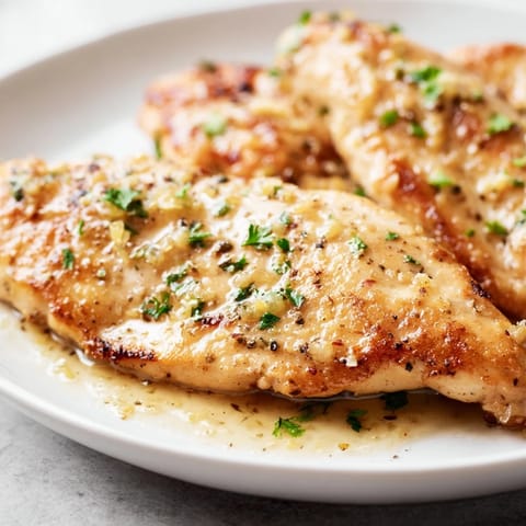 A close-up view of fork-tender Lemon Pepper Chicken served over creamy mashed potatoes with steamed green beans.