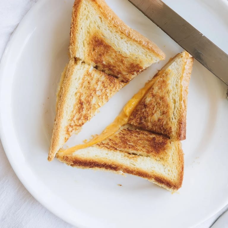 Freshly made Grilled Cheese Sandwich cut diagonally, steam rising from buttery bread and gooey cheese.