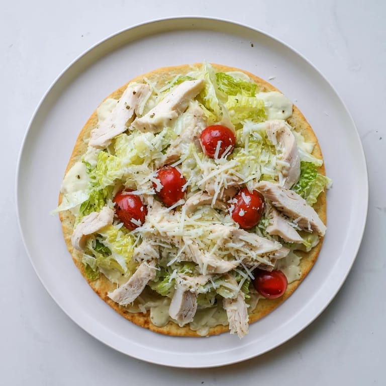 Savory Caesar Chicken Flatbread featuring tender grilled chicken, Caesar-dressed lettuce, and melted cheese on a golden crust.