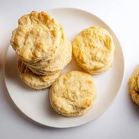 Golden-brown, tall Buttermilk Biscuits fresh from the oven with a melting butter pat on top. 