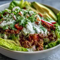 Vibrant Healthy Taco Bowl filled with seasoned ground beef, crisp romaine, diced tomatoes, and fresh cilantro.