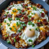 Loaded hash brown skillet with runny eggs and crispy bacon, perfect for brunch.